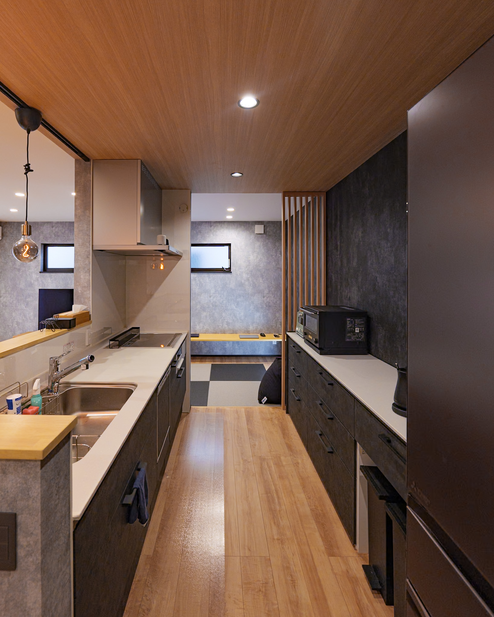 黒を基調としたキッチンの奥には、畳スペースが見える。